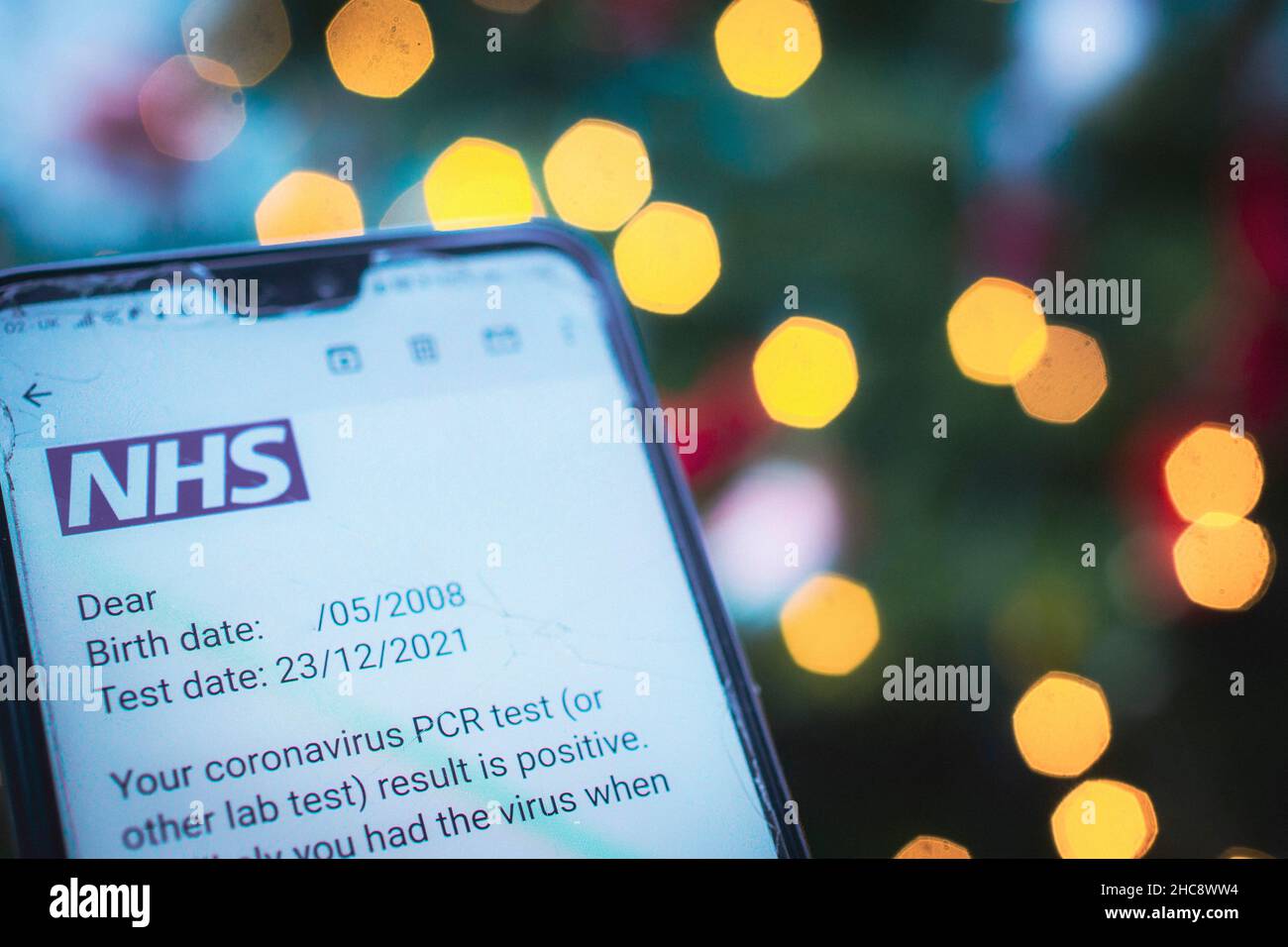 Nahaufnahme des Telefons mit positiver Meldung des NHS-Coronavirus-PCR-Tests Stockfoto
