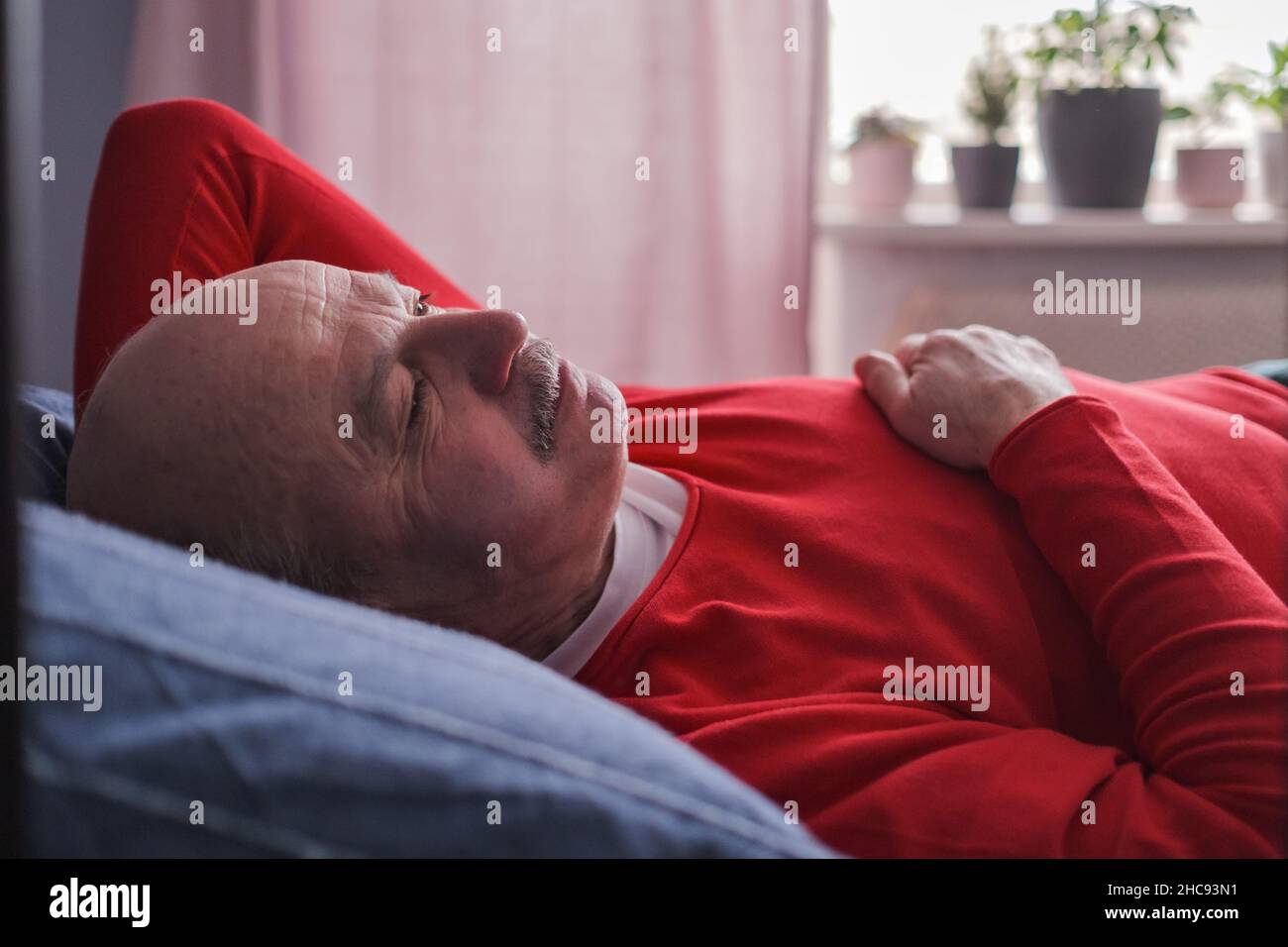 Der ältere Mann schlief morgens mit einem süßen Traum auf dem Bett im Schlafzimmer Stockfoto