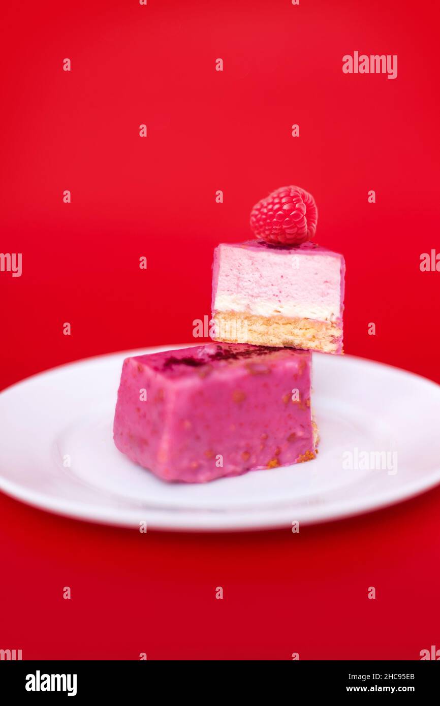 Mousse-Kuchen mit Himbeeren auf rotem Hintergrund. Stockfoto