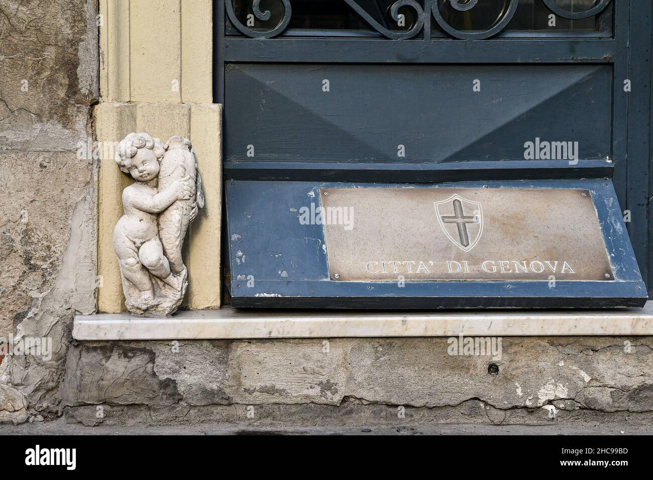 Detail der Eingangstür eines Palastes aus dem Jahr 1700, mit dem Stadtwappen und einer kleinen Statue, die einen Putto mit einem Fisch darstellt Stockfoto