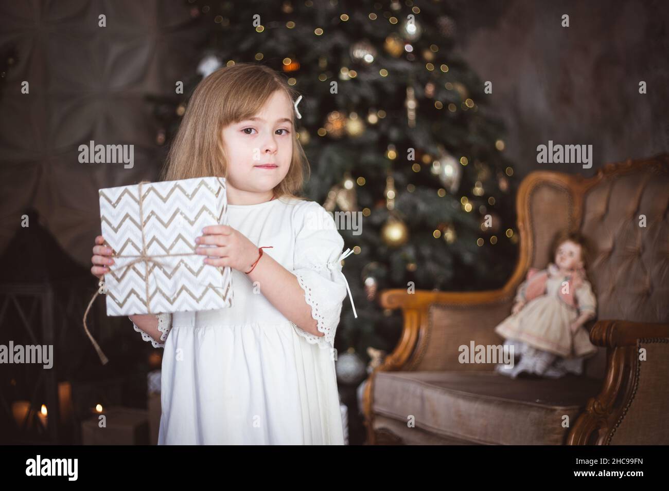 Nettes kleines Mädchen mit einem Weihnachtsgeschenk in ihren Händen. Winterferien, weihnachten und Neujahr. Stockfoto
