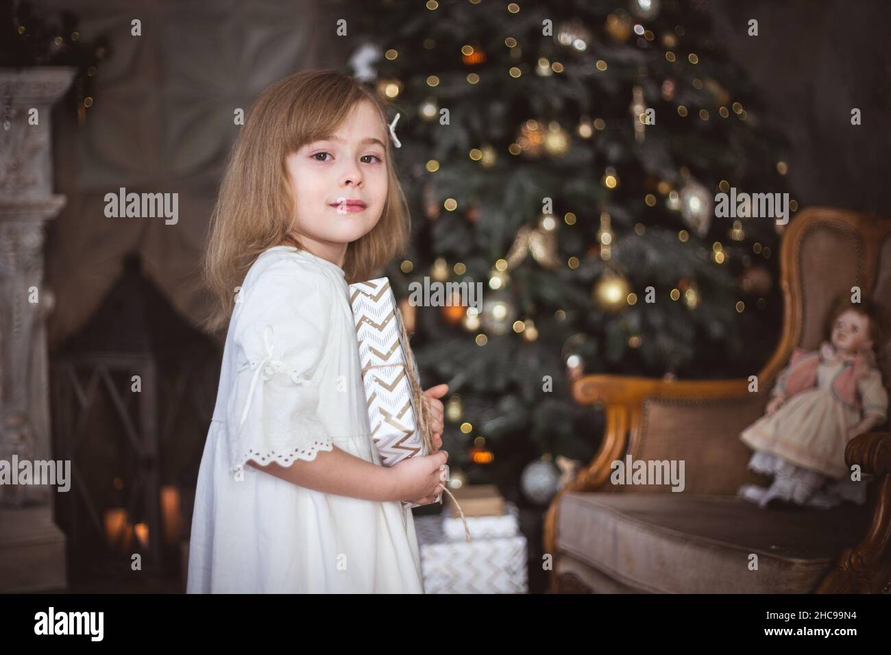 Nettes kleines Mädchen mit einem Weihnachtsgeschenk in ihren Händen. Winterferien, weihnachten und Neujahr. Stockfoto