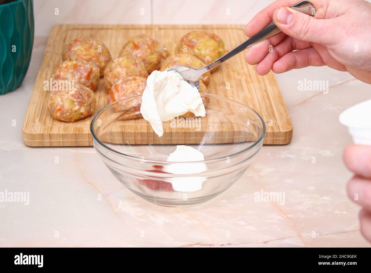 Ein Mann legt saure Creme zum Gießen, um faule Kohlrollen in einem langsamen Herd zu kochen. Stockfoto