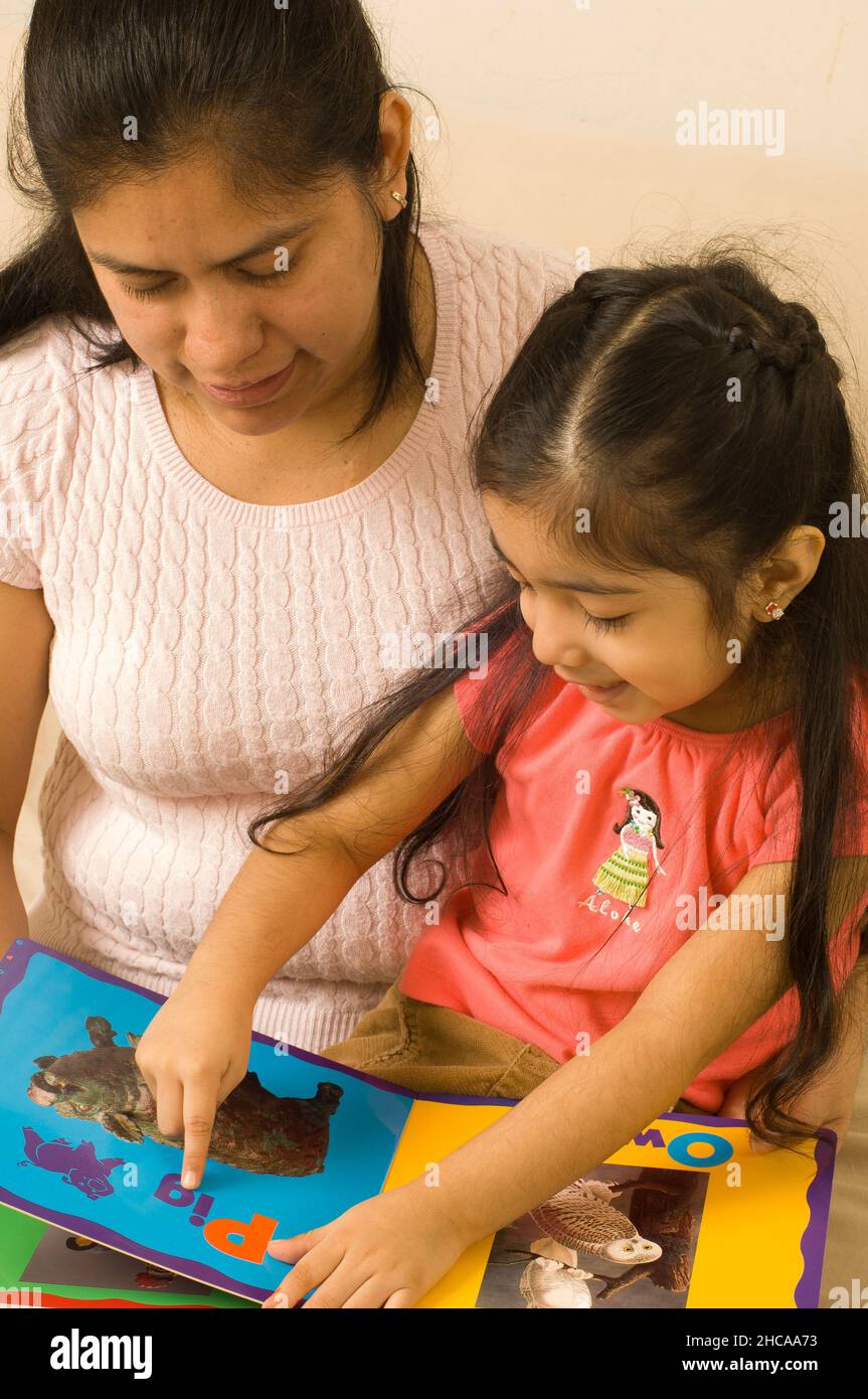 3-jähriges Mädchen zu Hause mit Mutter Interaktion Buch lesen und sprechendes Kind zeigt auf Illustration Stockfoto