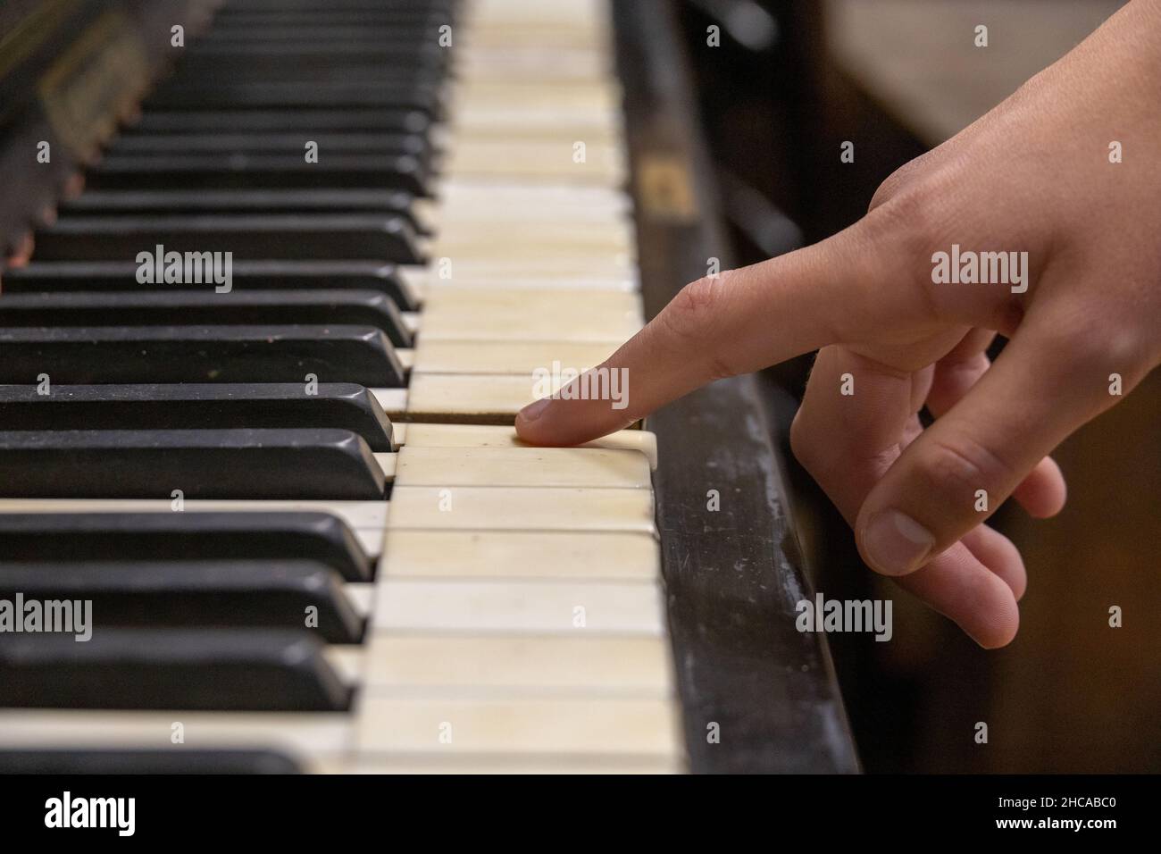Nahaufnahme eines Fingers, der eine alte Klaviertaste drückt Stockfoto