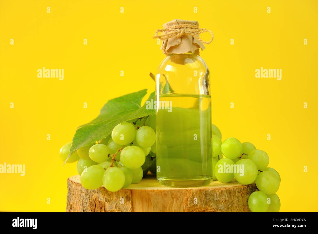 Traubenkernöl.Base kosmetisches Öl für Massage und Pflege für Gesicht und Körper. Flasche und Bund von grünen Trauben auf einer gelben background.Organic natürliche Traube Stockfoto