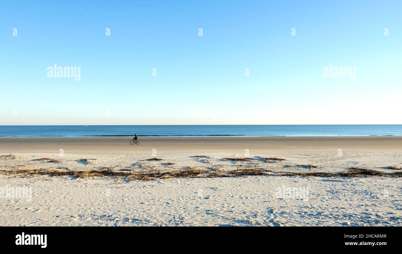 Ein Single-Bike-Fahrer an einem einsamen, klaren Sandstrand in Hilton Head, South Carolina, USA; Spaß, Bewegung und Entspannung an einem sonnigen Tag. Stockfoto