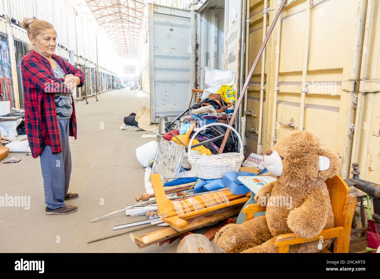 Kasachische Frau, die an einem normalen Tag auf dem leeren Flohmarkt im Freien Teddybär unter verschiedenen Gegenständen verkauft. Almaty, Kasachstan Stockfoto