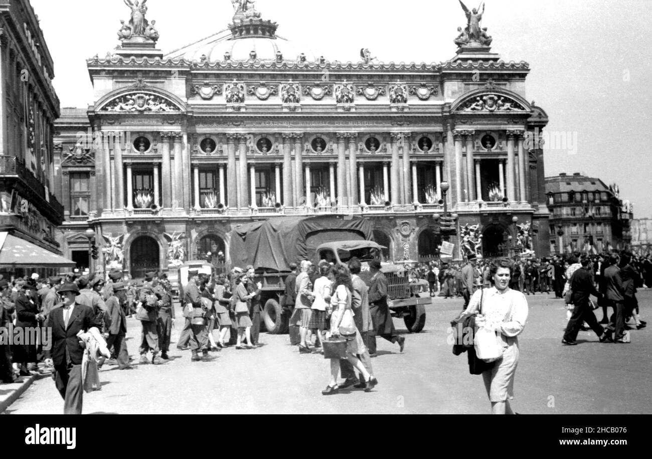 Pariser feiern am 3 1945. April auf dem Place de L’Opera. Dies war ein Tag der Feierlichkeiten in Paris, der mit 100.000 Menschen gipfelte, die Charles De Gaulle bei der Wiederbelebung des französischen Militärs beobachteten. De Gaulle restaurierte die Farben von 131 Einheiten der französischen Kampfdienste. Der schwedische Journalist Sven Auren berichtete: „an jenem Aprilmorgen waren die Pariser auf dem Place de la Concord zu dem Mann raus…, wo sich ein veritabler Wald aus weißen Flaggenstäben befand, die alle die Trikolore flogen.“ Stockfoto