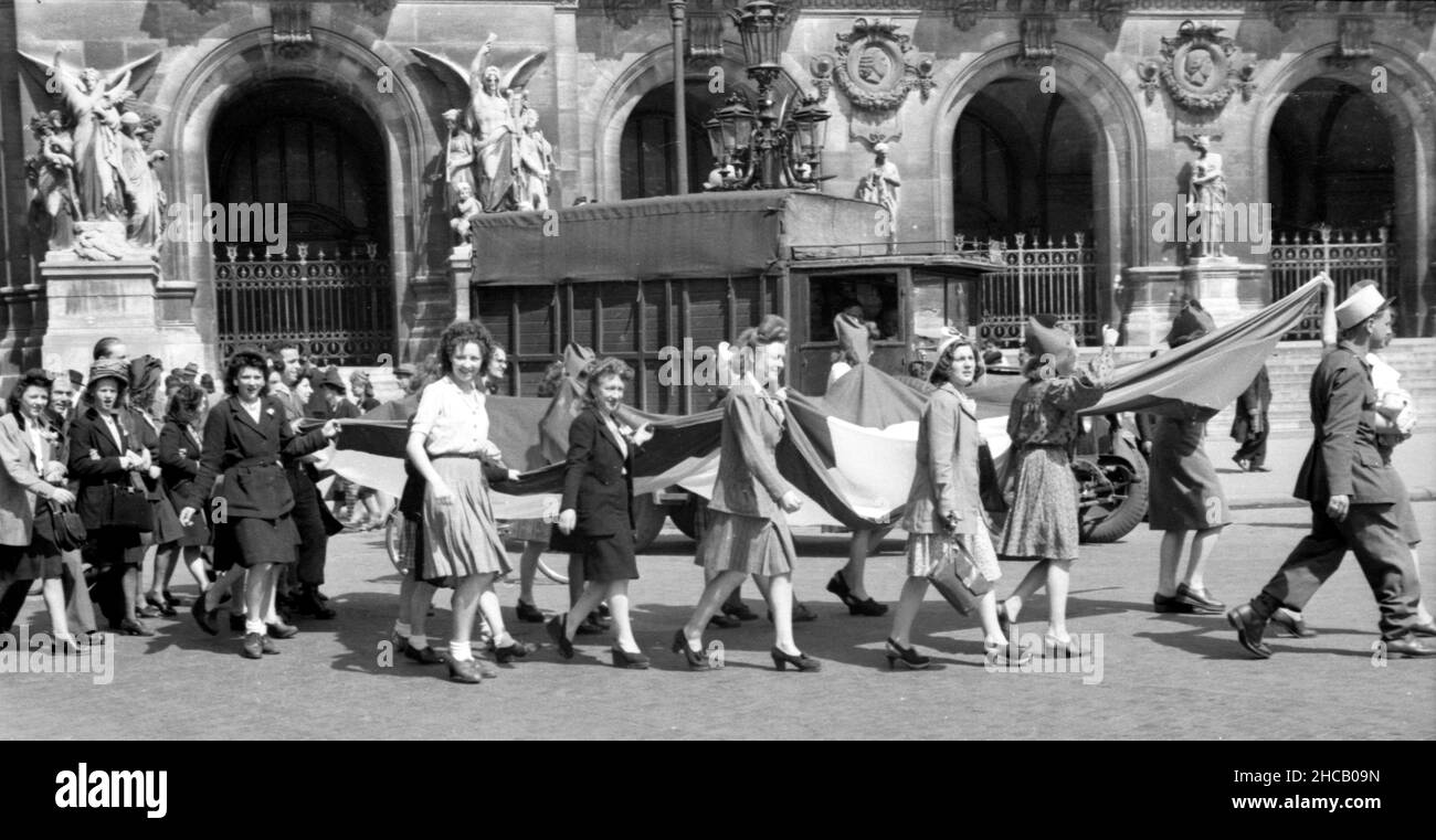Frauen ziehen mit großer französischer Flagge als pariserinnen am 3 1945. April auf den Place de L’Opera. Dies war ein Tag der Feierlichkeiten in Paris, der mit 100.000 Menschen gipfelte, die Charles De Gaulle bei der Wiederbelebung des französischen Militärs beobachteten. De Gaulle stellte die Farben von 131 Einheiten der französischen Kampfdienste wieder her. Der schwedische Journalist Sven Auren berichtete: „an jenem Aprilmorgen waren die Pariser auf dem Place de la Concorde zu dem Mann raus…dort war ein wahrer Wald aus weißen Flagstaffs, die alle die Trikolore flogen.“ Stockfoto