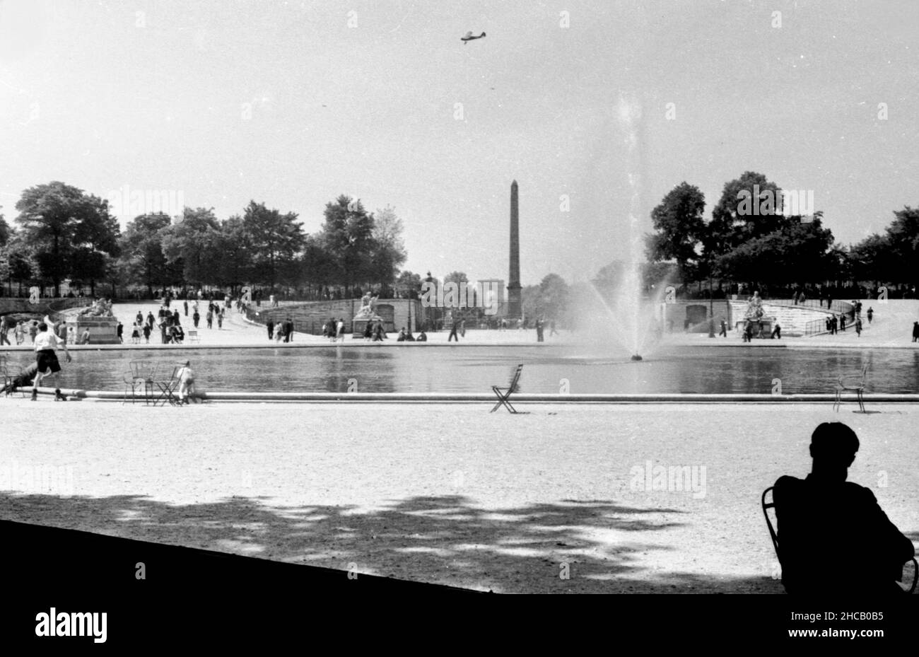 Feier am Brunnen auf dem Place de la Concorde, April 3 1945. Ein Flugzeug kreist um den Kopf.Dies war ein Tag der Feier in Paris, der mit 100.000 Menschen gipfelte, die Charles De Gaulle bei der Wiederbelebung des französischen Militärs beobachteten. De Gaulle stellte die Farben von 131 Einheiten der französischen Kampfdienste wieder her. Der schwedische Journalist Sven Auren berichtete: „an jenem Aprilmorgen waren die Pariser auf dem Place de la Concorde zu dem Mann raus…dort war ein wahrer Wald aus weißen Flagstaffs, die alle die Trikolore flogen.“ Stockfoto