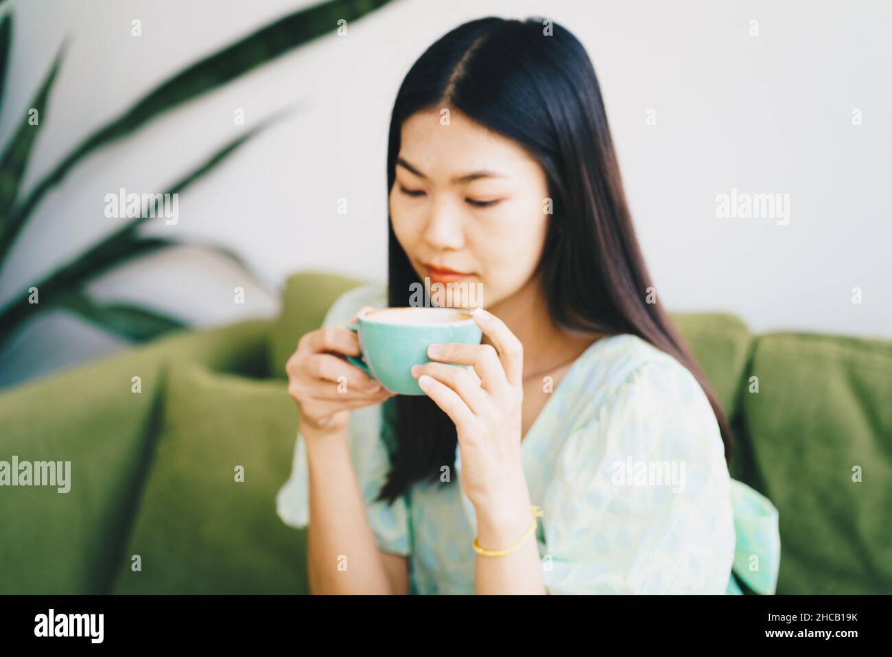 Schöne Frauen sitzend auf grünem Sofa trinken heißen Latte Kaffee Aroma Getränk Stockfoto