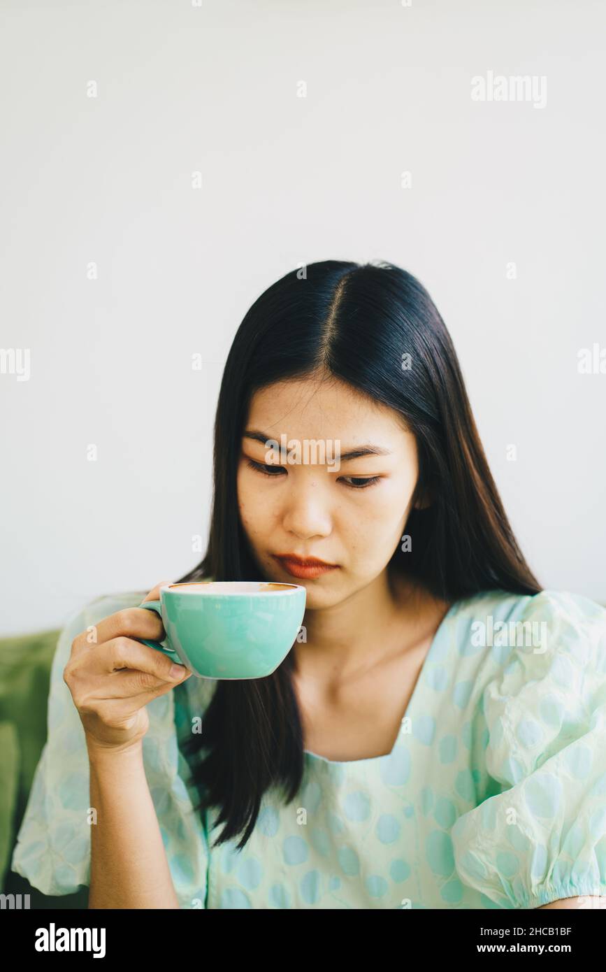 Schöne Frauen sitzend auf grünem Sofa trinken heißen Latte Kaffee Aroma Getränk Stockfoto