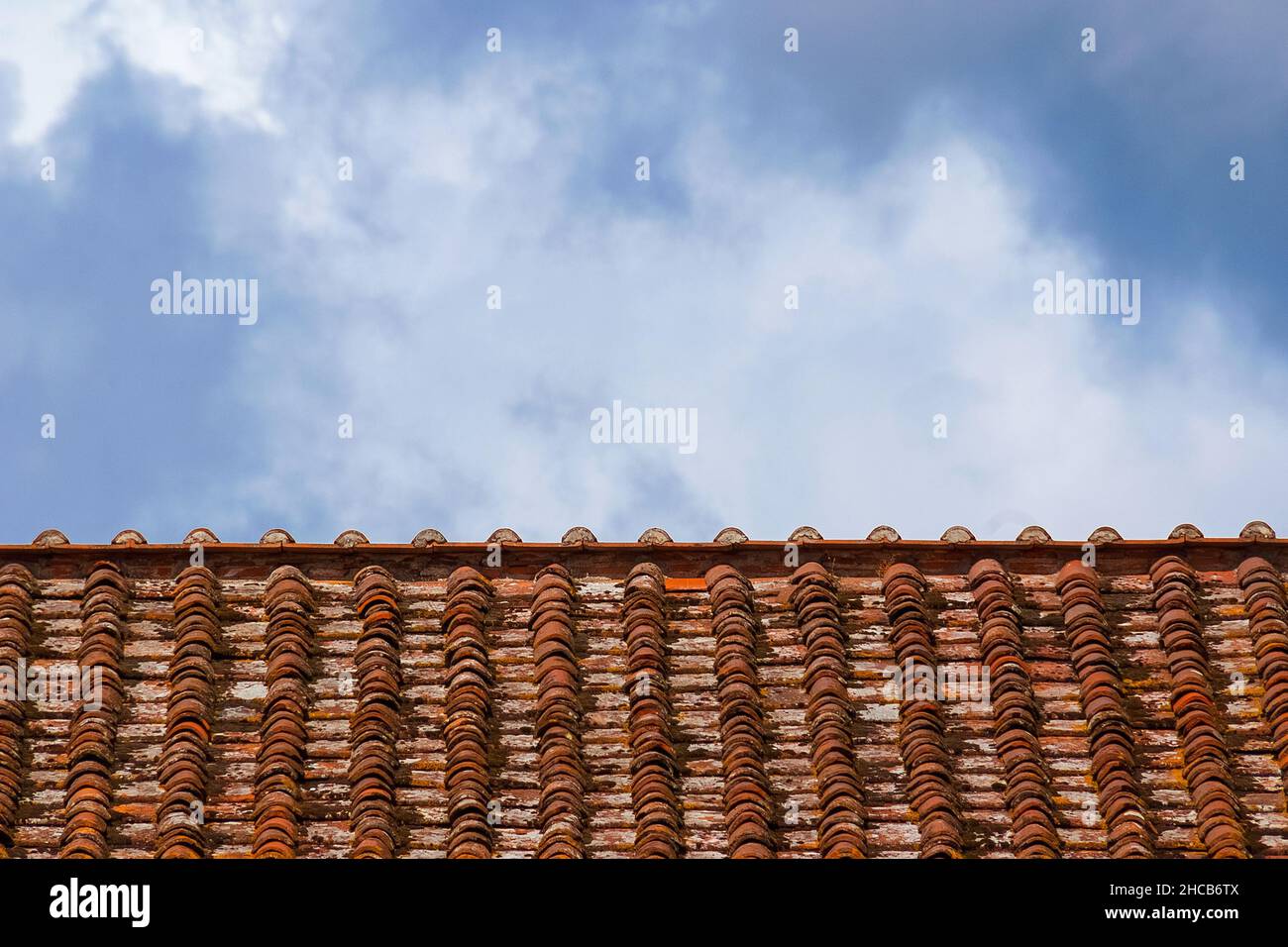 Alte rote und orange Dachziegel mit Wolken oben als Hintergrund Stockfoto