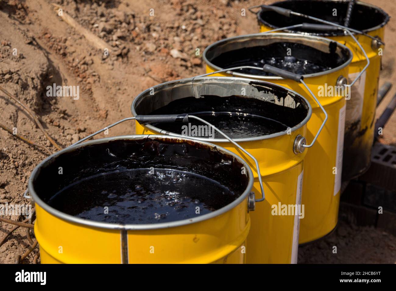Bitumenmastix in Eimern. Schützender Bitumenmastix für Betonpflaster. Material für die Abdichtung des Fundaments. Stockfoto