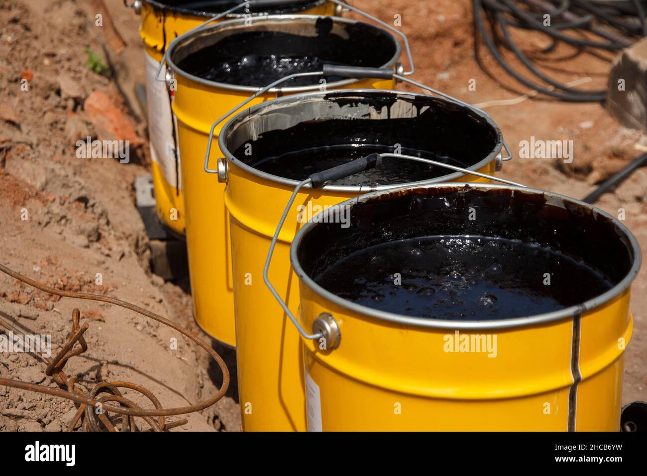 Bitumenmastix in Eimern. Schützender Bitumenmastix für Betonpflaster. Material für die Abdichtung des Fundaments. Stockfoto