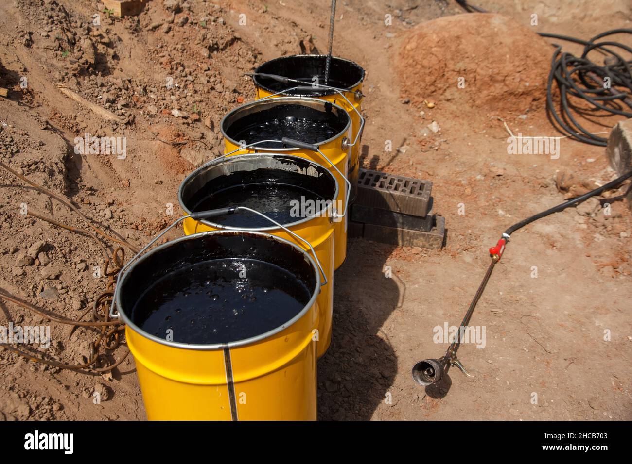 Bitumenmastix in Eimern. Schützender Bitumenmastix für Betonpflaster. Material für die Abdichtung des Fundaments. Stockfoto