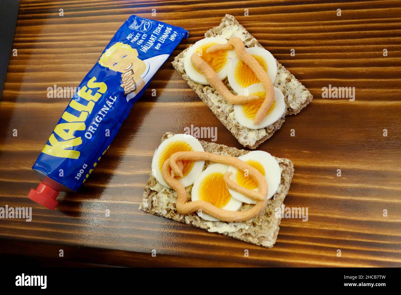 Schwedisches Sandwich (Smörgåss) mit Eierscheiben und Kalles Kaviar auf dem knusprigen Brot (knäckebröd). Auf dem verbrannten Holzhintergrund. Stockfoto