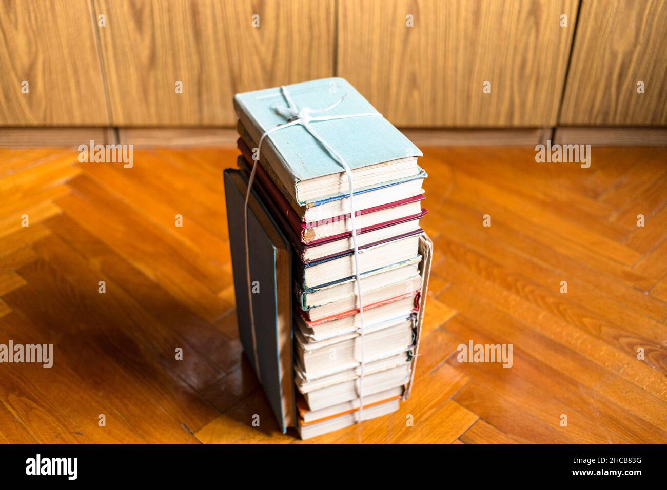 Oben Blick auf Stapel von alten Büchern mit Garn auf Parkettboden im Wohnzimmer gebunden Stockfoto