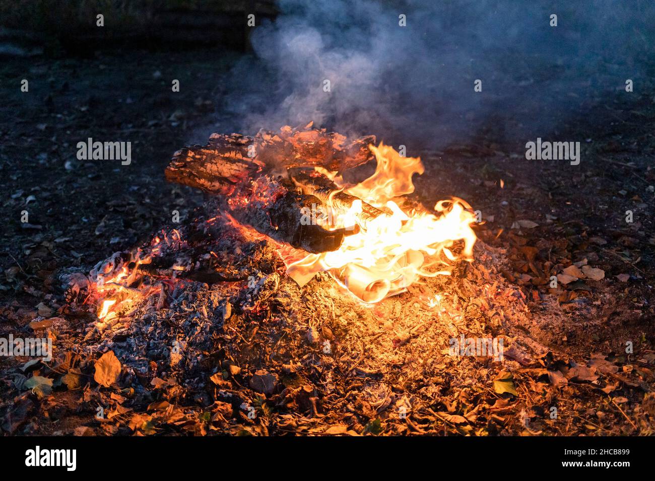 In der Abenddämmerung werden Feuerwälder auf einem Haufen Asche im Garten des Landes geburten Stockfoto
