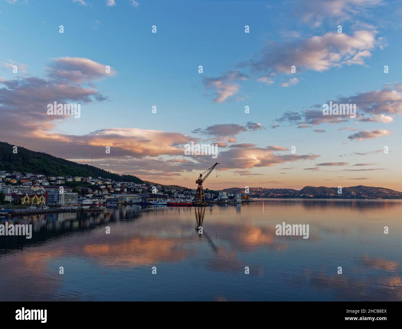 Morgendämmerung an der Bergens Waterfront mit Blick auf den alten Fischerhafen mit seinem Onshore-Kran und Wolken, die sich im Nockenwasser spiegeln Stockfoto