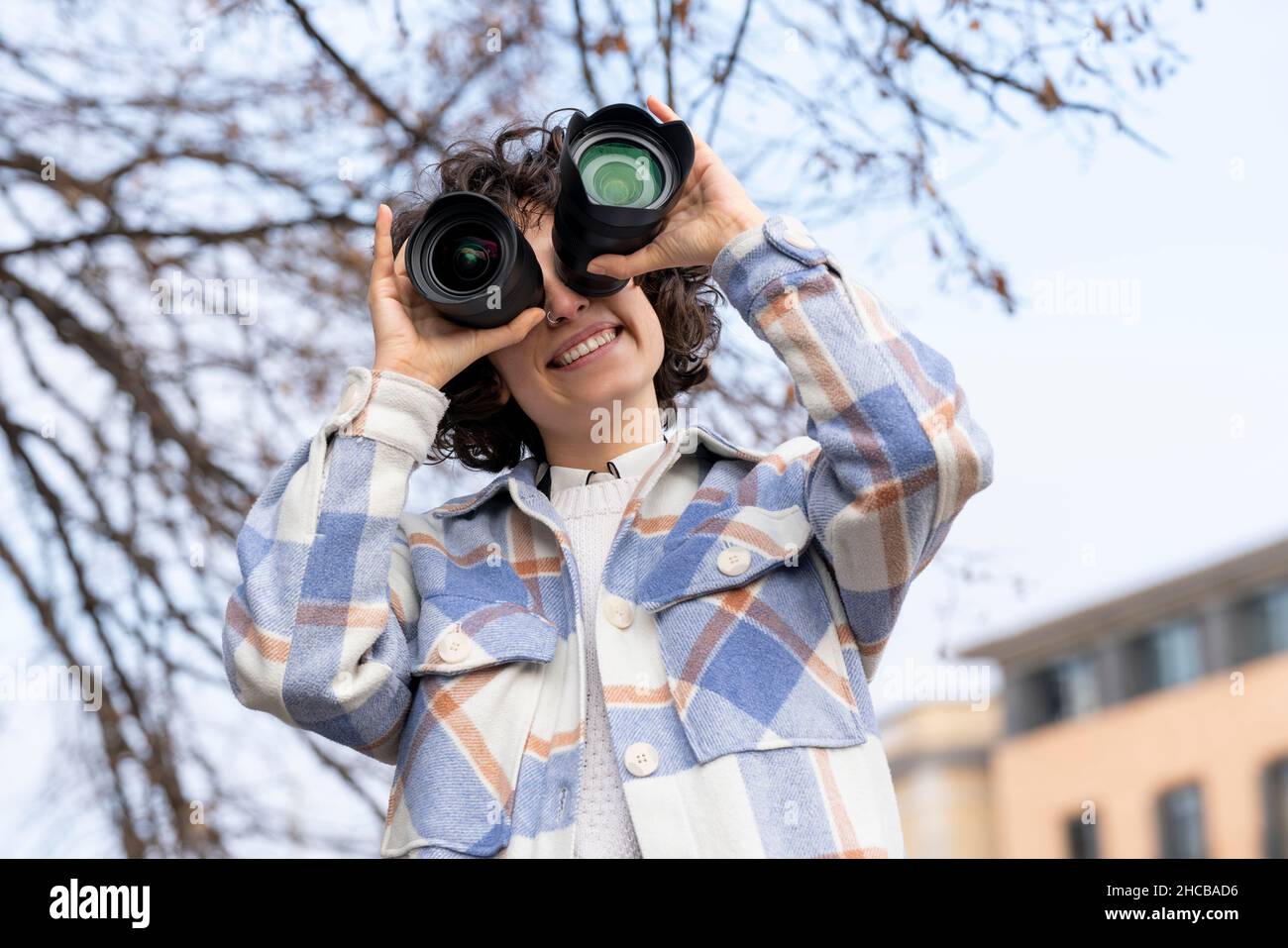Junge Brünette lockiges Haar Frau herumzutäuschen mit zwei Foto-Linsen Stockfoto