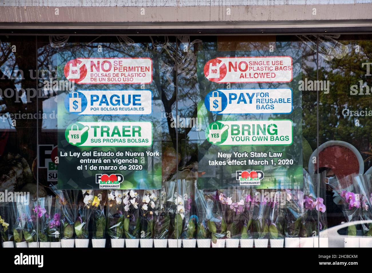 Schilder auf dem Supermarktfenster, auf denen steht, dass Plastiktüten verboten seien, Papiertüten kosten würden und Kunden drängen würden, ihre eigenen mitzubringen. In Corona, Queens NYC Stockfoto