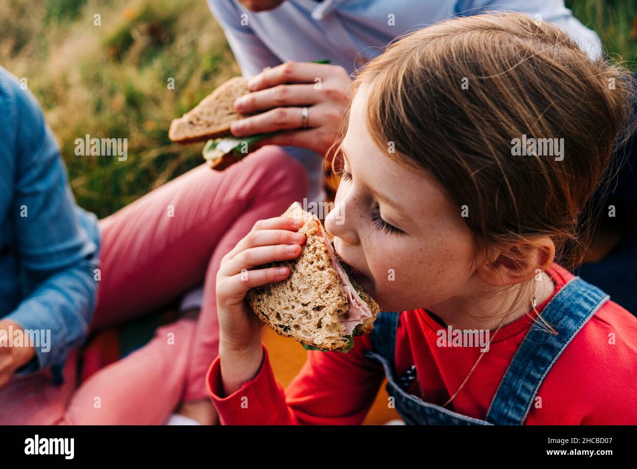 Mädchen essen Sandwich mit Eltern im Park Stockfoto