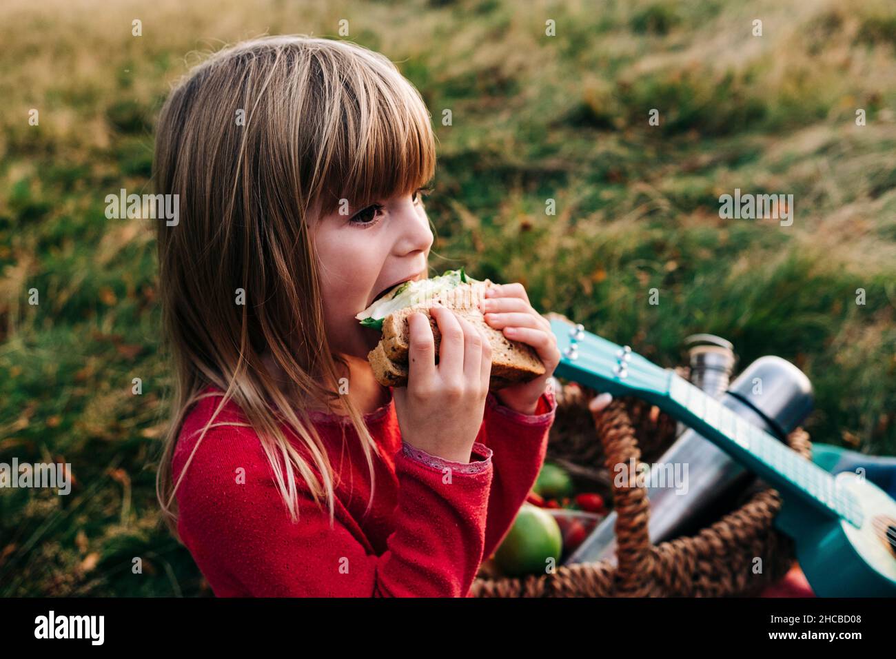 Blonde Mädchen essen Sandwich auf Gras Stockfoto