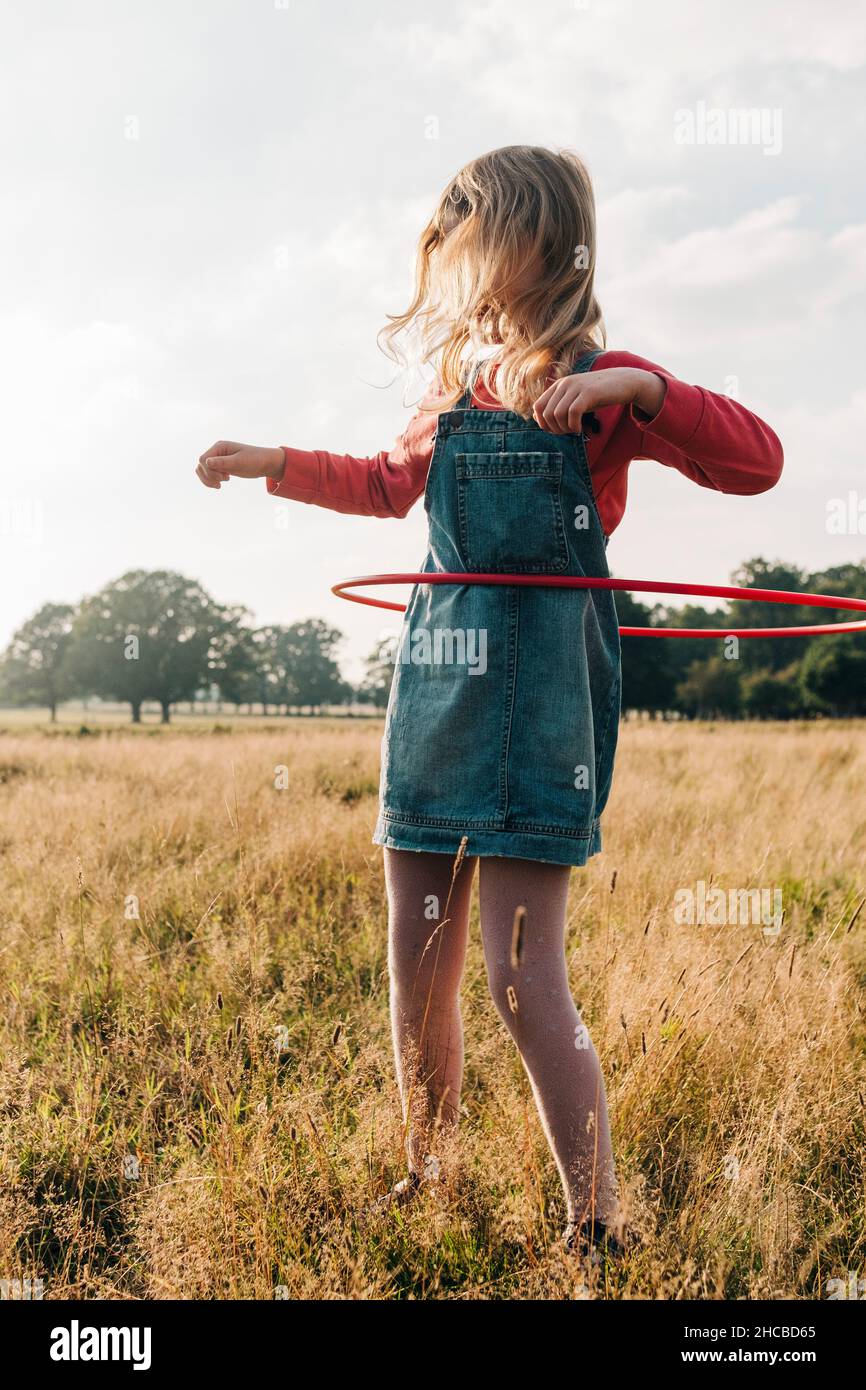 Mädchen spielt am Wochenende mit Hula Hoop im Park Stockfoto