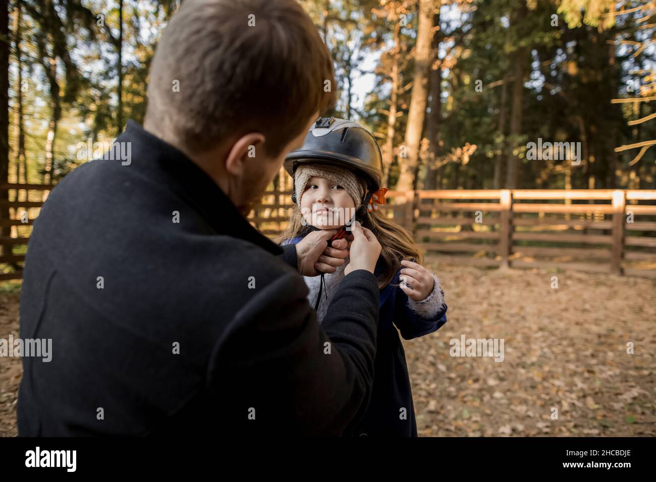 Vater, der auf dem Spielplatz einen Schutzhelm auf die Tochter setzt Stockfoto