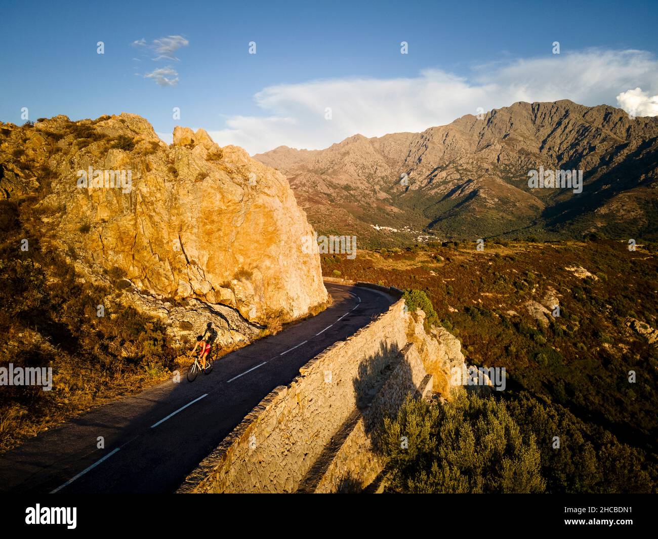 Sportlerin, die Fahrrad auf der Straße durch die Berge fährt Stockfoto