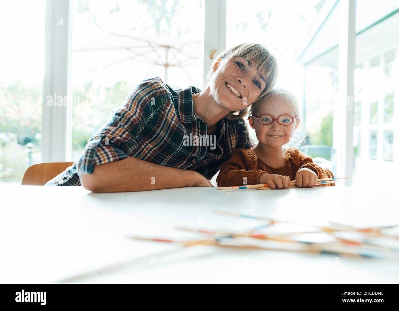 Lächelnde Frau mit gekreuzten Armen, gelehnt an die Tür Stockfoto