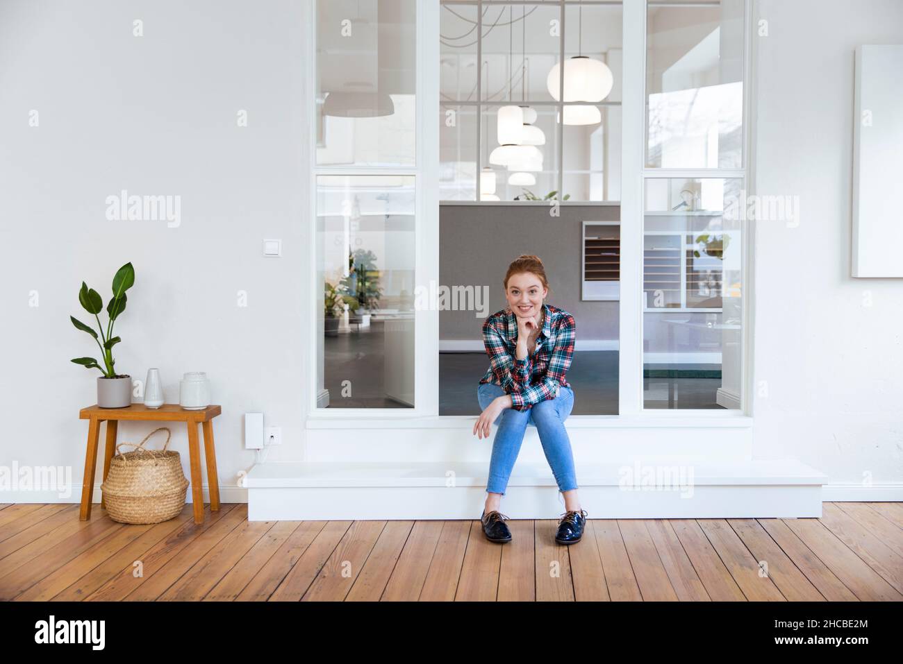 Junge Geschäftsfrau, die am Eingang sitzt Stockfoto