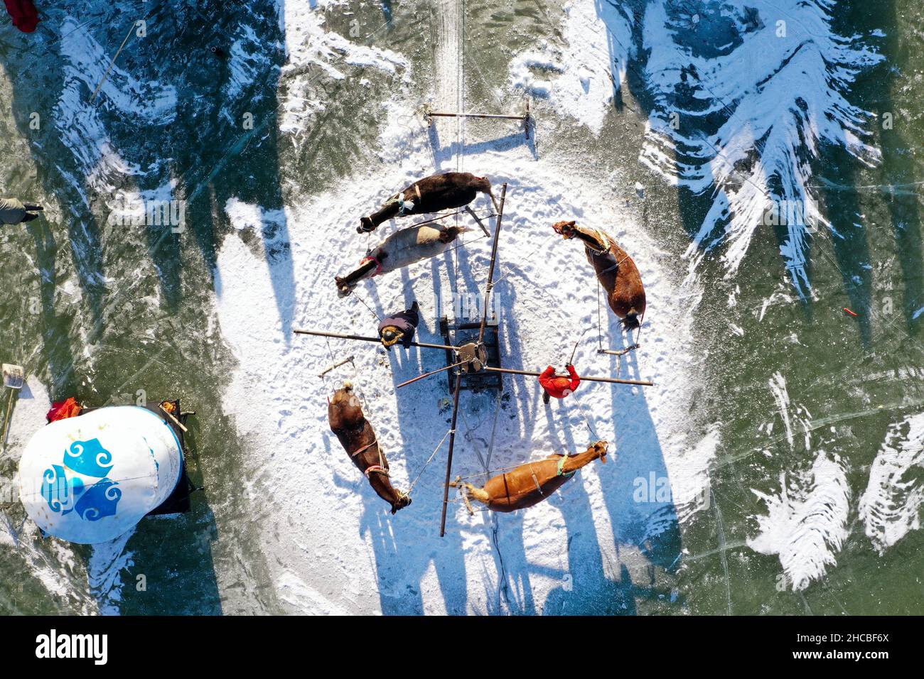 Songyuan. 26th Dez 2021. Luftaufnahme vom 26. Dezember 2021 zeigt Fischer, die Fische am Chagan-See in Songyuan, nordöstlich der Provinz Jilin, fangen. Jahrhundertelang haben Fischer und Frauen, die am See leben, die Tradition des Eisfischens am Leben erhalten - man bohrt Löcher durch dickes Eis und legt Netze unter, um Fische zu fangen. Die Technik wurde als eine Form des immateriellen Kulturerbes auf nationaler Ebene aufgeführt. Quelle: Yan Linyun/Xinhua/Alamy Live News Stockfoto