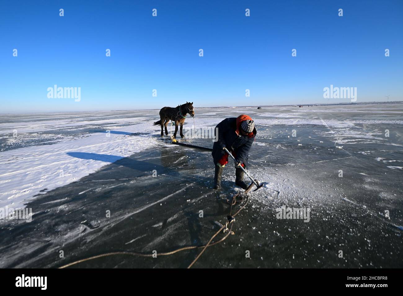 Songyuan, Chinas Provinz Jilin. 26th Dez 2021. Ein Fischer bereitet sich auf die Fischernte am Chagan-See in Songyuan, nordöstlich der Provinz Jilin, vor, 26. Dezember 2021. Jahrhundertelang haben Fischer und Frauen, die am See leben, die Tradition des Eisfischens am Leben erhalten - man bohrt Löcher durch dickes Eis und legt Netze unter, um Fische zu fangen. Die Technik wurde als eine Form des immateriellen Kulturerbes auf nationaler Ebene aufgeführt. Quelle: Yan Linyun/Xinhua/Alamy Live News Stockfoto