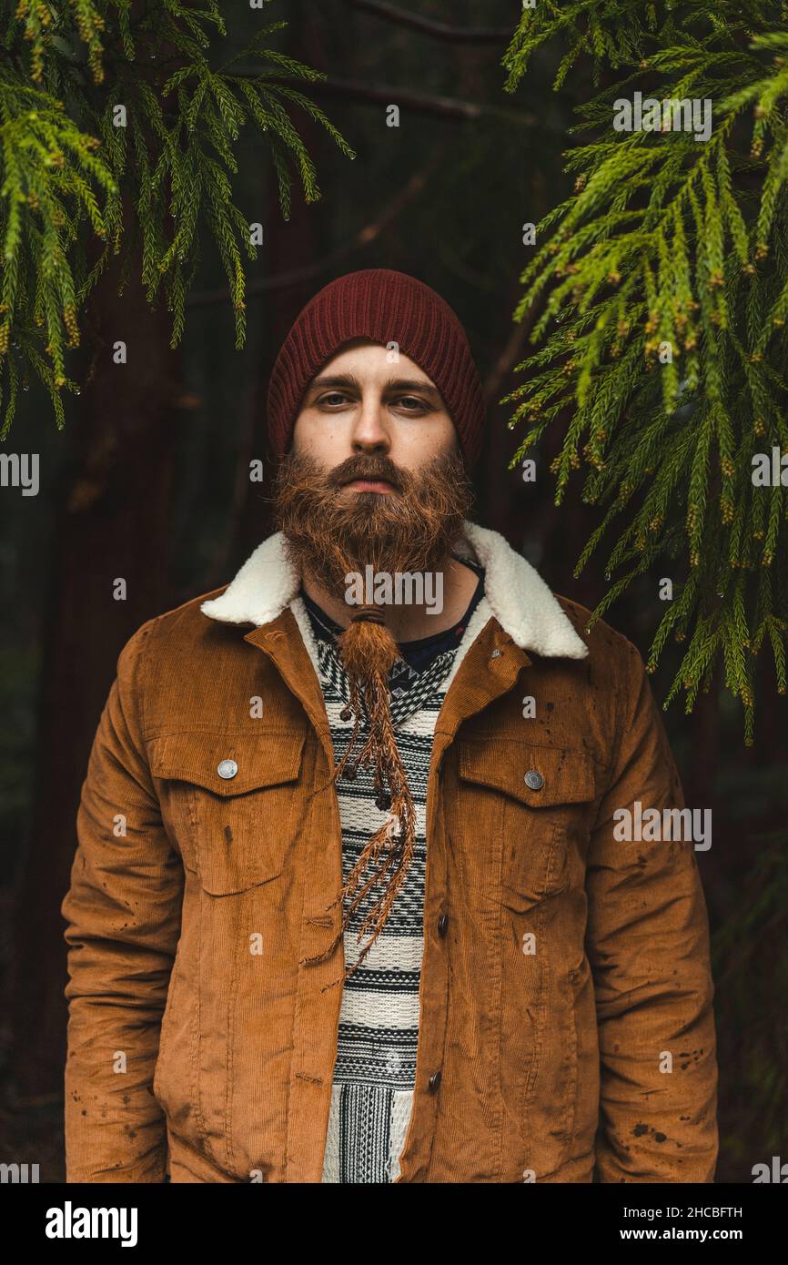 Junger bärtiger Mann mit Jacke im Wald Stockfoto