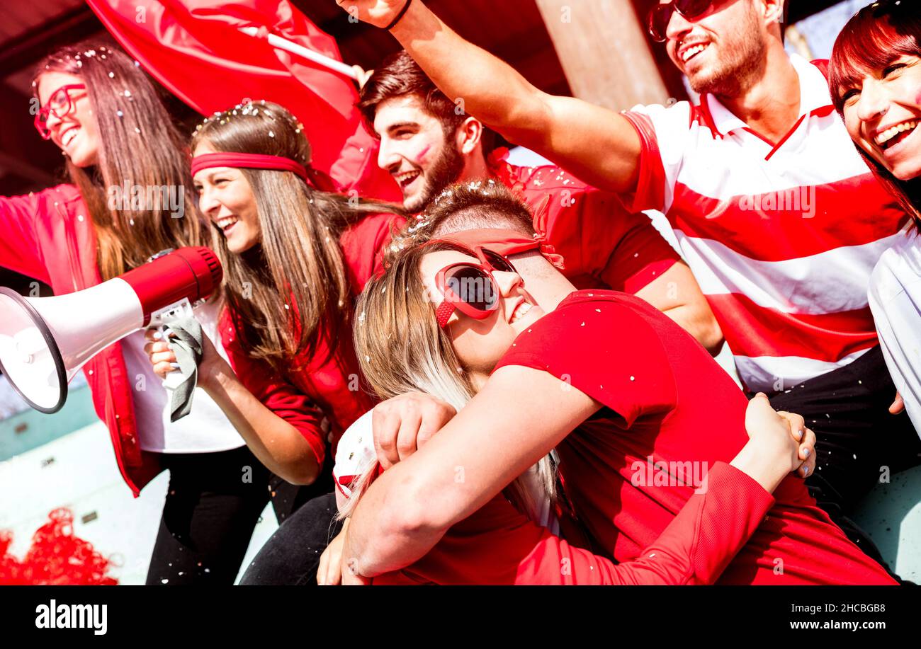 Freunde Fußballfans Fans umarmen sich gegenseitig beim Fußballspiel-Event im Stadion - Junge Leute Gruppe mit roten T-Shirts haben Spaß aufgeregt Stockfoto