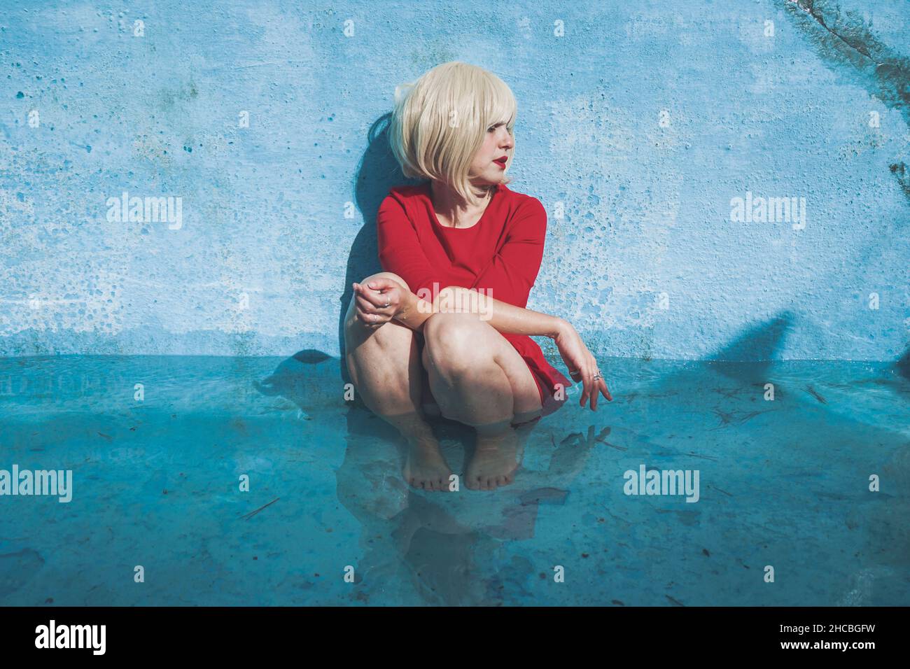 Traurige Frau, die mit geschlossenen Augen im blauen Swimmingpool saß Stockfoto
