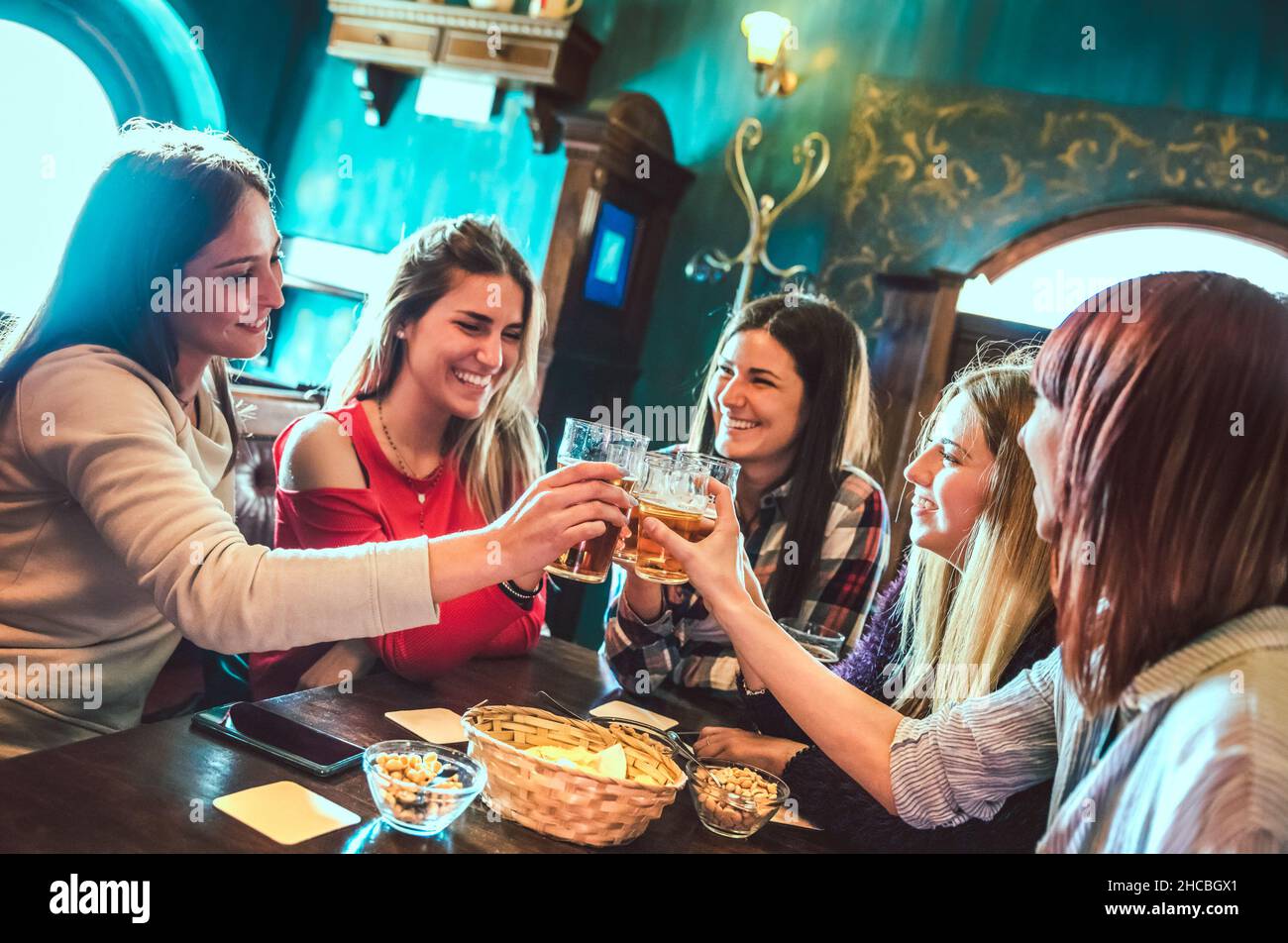 Fröhliche Freundinnen beim Biertoasten im Restaurant der Brauerei Bar - Freundschaftskonzept für Frauen mit jungen Frauen, die gemeinsam in einem coolen Vintage Pub echten Spaß haben Stockfoto