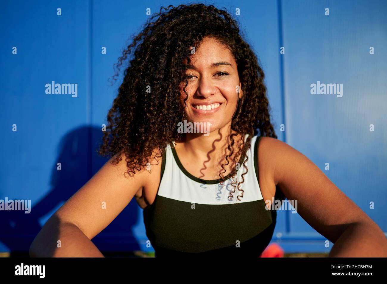 Junge Sportlerin lächelt vor der blauen Wand Stockfoto