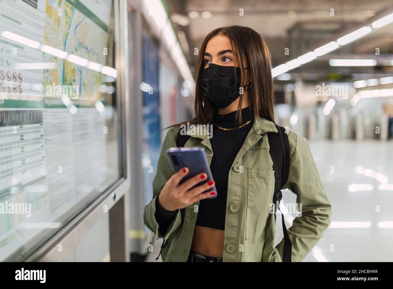 Frau mit Gesichtsmaske und Handy, die Karte in der U-Bahn überprüft Stockfoto