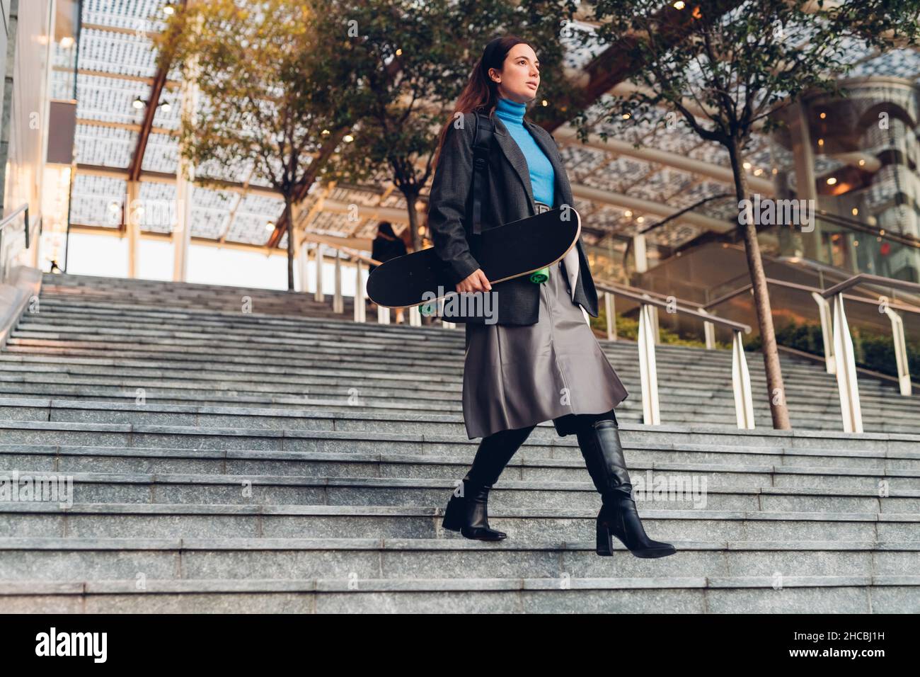 Geschäftsfrau mit Skateboard, die beim Bauen die Stufen hinuntergeht Stockfoto