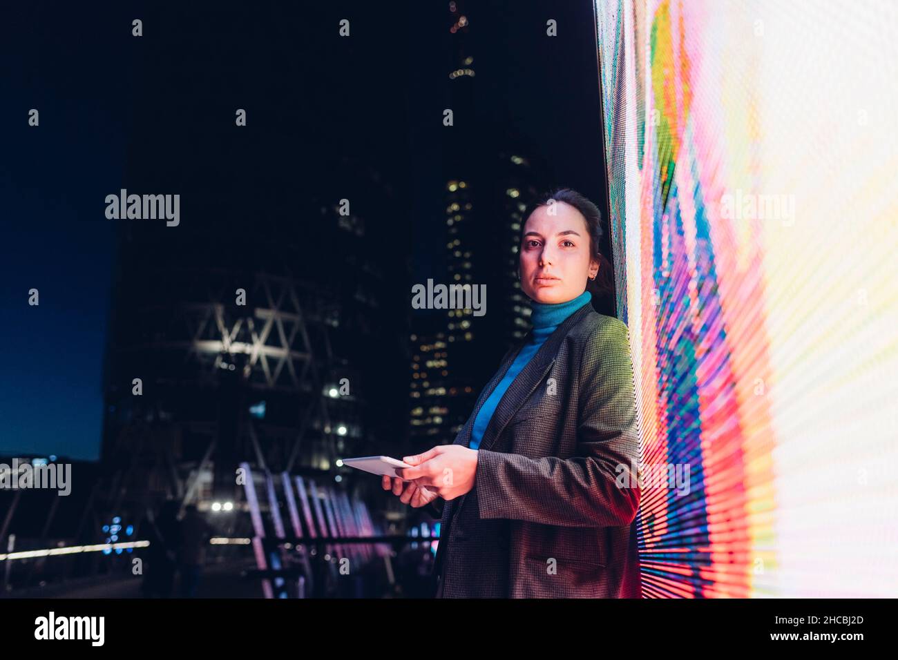 Geschäftsfrau hält Tablet-PC am interaktiven Informationsstand in der Nacht Stockfoto