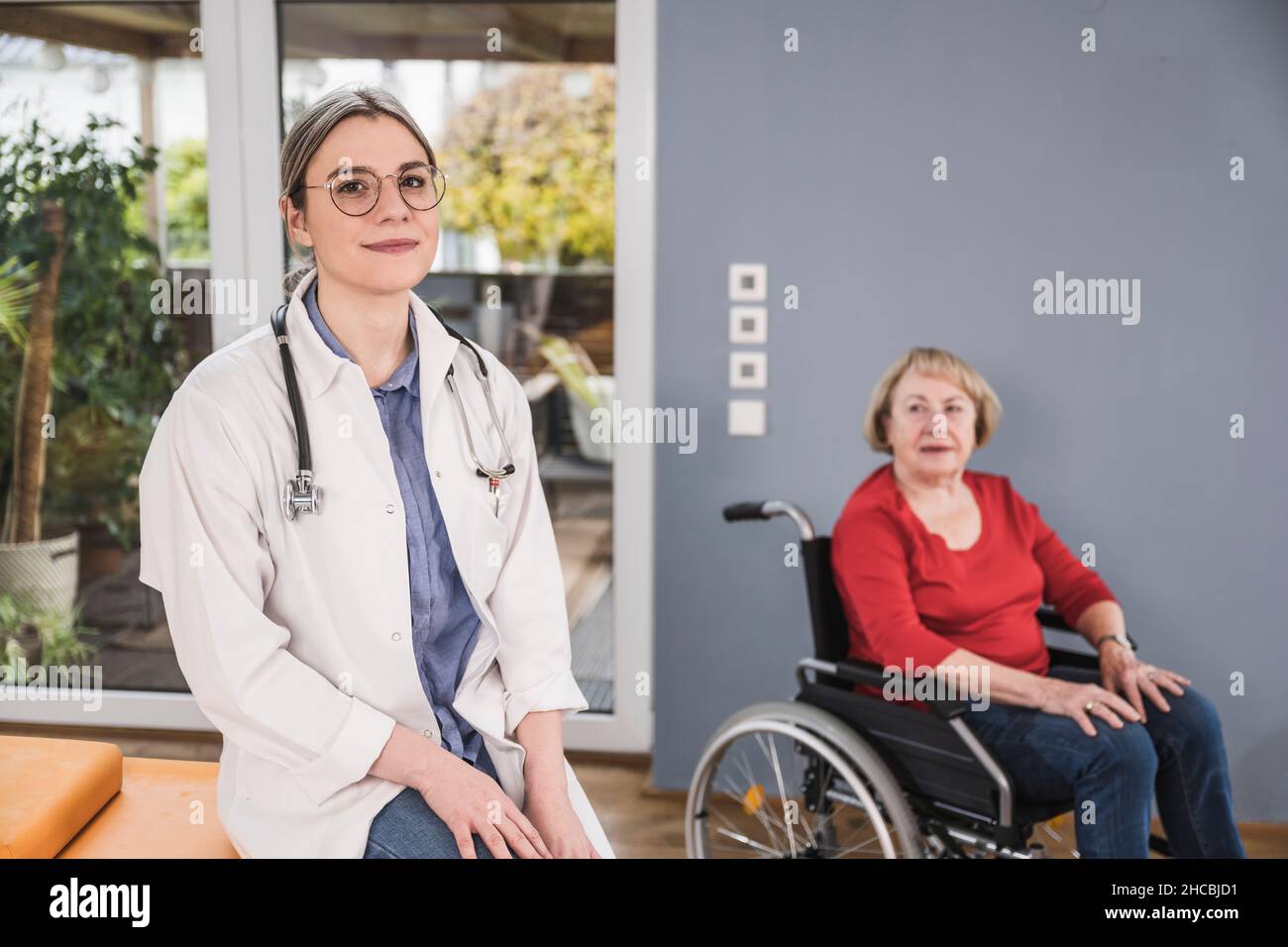 Lächelnder Arzt, der zu Hause mit einer behinderten Frau