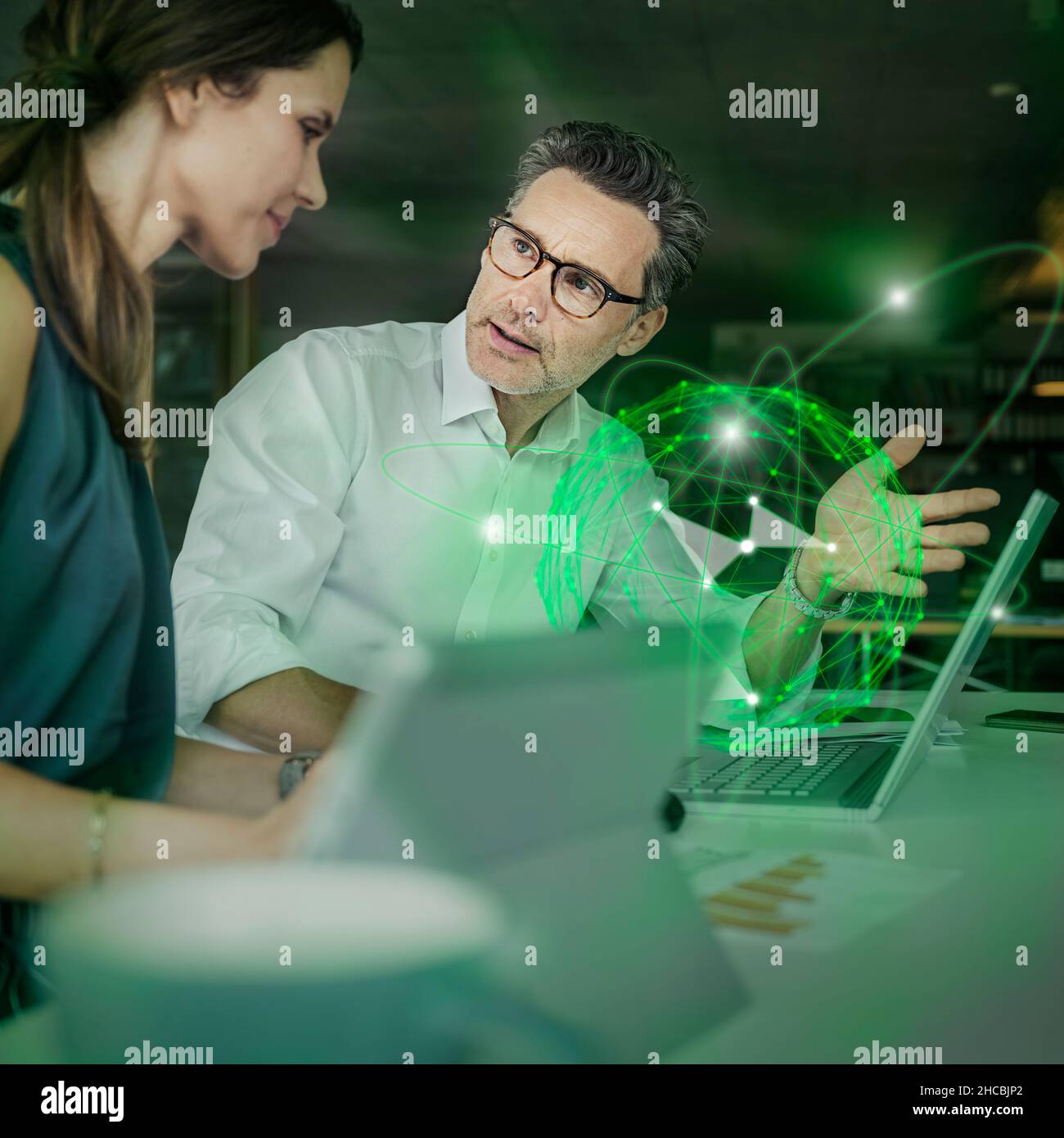 Geschäftsmann erklärt Kollegen im Büro ein futuristisches Hologramm Stockfoto
