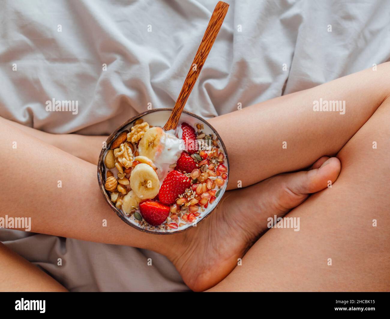 Schale mit Fruchtjoghurt auf den Beinen der Frau zu Hause Stockfoto