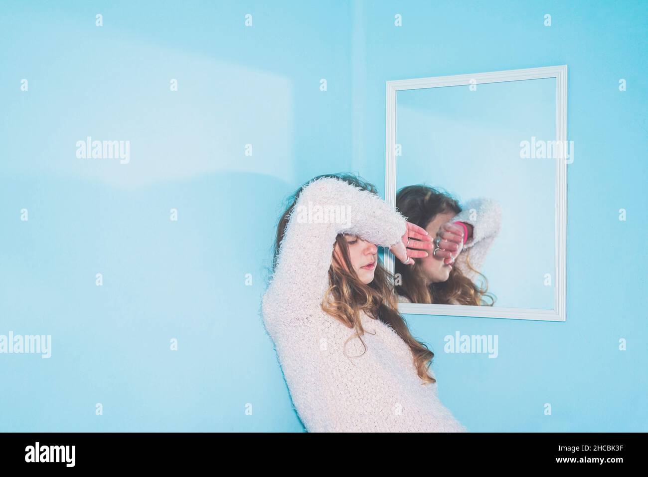 Gelangweilte Frau mit der Hand auf dem Kopf, die sich zu Hause am Spiegel lehnt Stockfoto