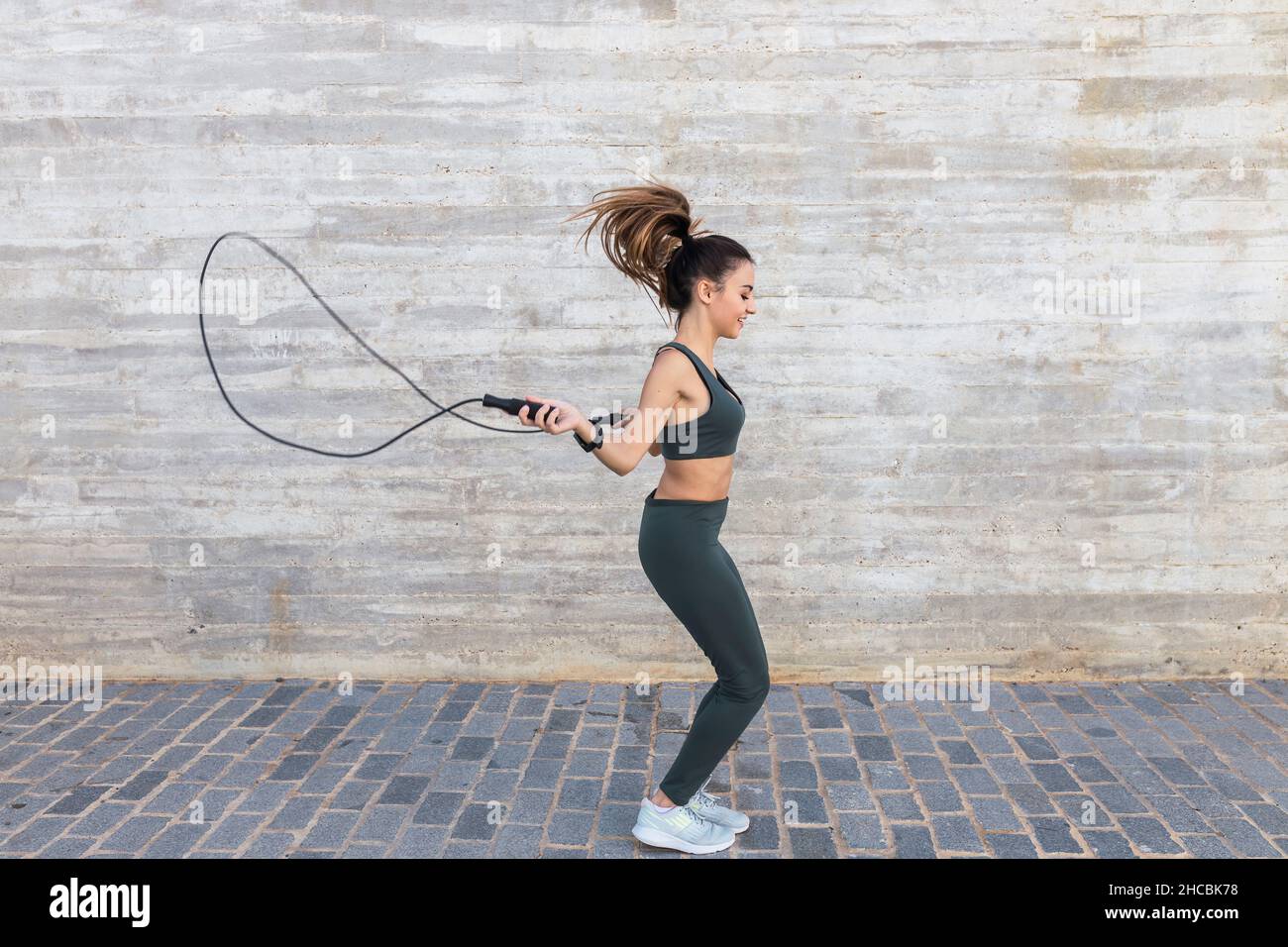 Sportlerin mit Seilspringen an der Wand Stockfoto