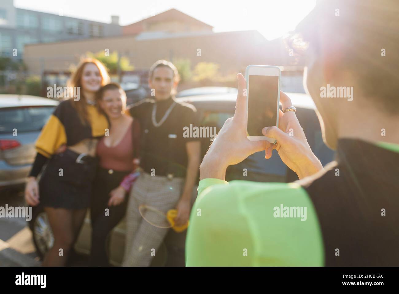 Mann, der Freunde am sonnigen Tag über das Mobiltelefon fotografiert Stockfoto